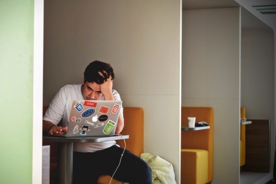 Student in front of laptop receiving low GMAT score. Frustrated student looking at GMAT results